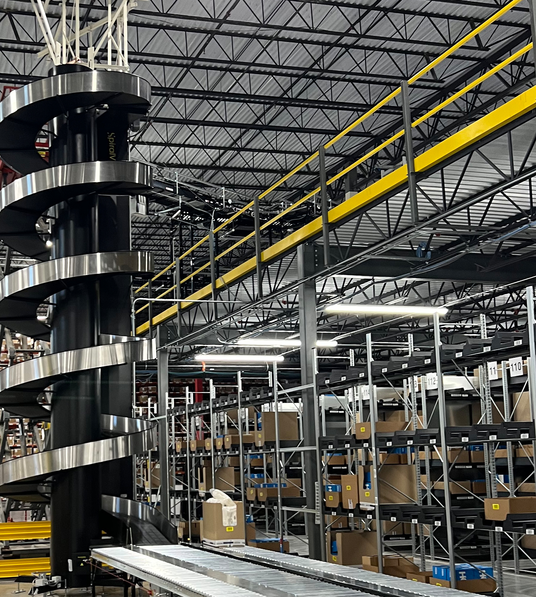 Tall spiral conveyor tower and elevated conveyor lines in a warehouse